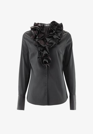 Schwarze Bluse mit langen Ärmeln und Rüschenspiegel, aus glattem Stoff. Verfügt über einen Knopfverschluss und eine einzelne Tasche auf der linken Seite.