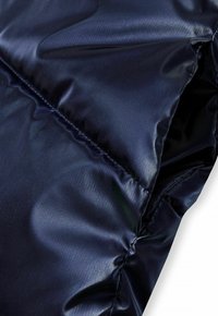 Jūras zila pūkainā jaka ar gludu, mirdzošu tekstūru. Iekļauj šuvju šuvumus un nedaudz krunkotu izskatu. Viegls un izolējošs.