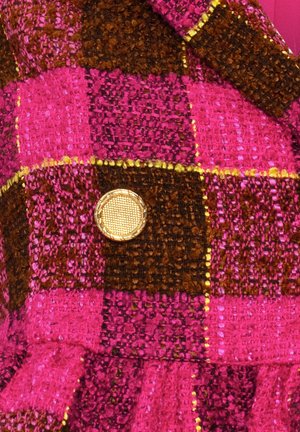 Tissu écossais rose et marron avec un tissage texturé, mettant en avant un bouton doré avec un motif en maillage au centre.