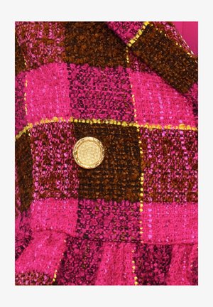 Tissu écossais rose et marron avec un tissage texturé, mettant en avant un bouton doré avec un motif en maillage au centre.