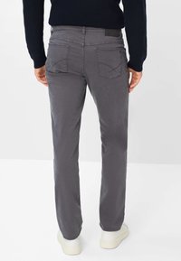 Pantaloni in misto cotone grigi con taglio dritto, vita elastica e due tasche decorative sul retro. Abbinati a sneaker bianche.