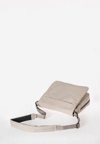 Borsa a tracolla beige con una texture liscia e opaca. Presenta un cappuccio pieghevole e una tracolla regolabile, con una tasca con zip sul lato.