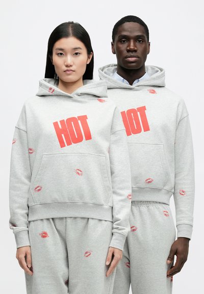 Grå hoodies med stort rött "HOT"-tryck och läppstiftskysstmönster. Har en framficka och avslappnad passform, kombinerade med matchande sweatpants.