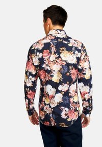 Camicia a maniche lunghe con sfondo blu navy e un vivace motivo floreale in tonalità di rosa, bianco e giallo. Tessuto liscio, colletto con bottoni.