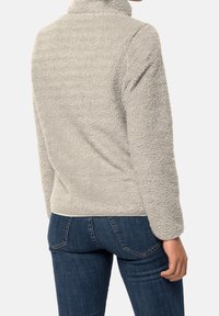 Ljusgrå fleecepullover med hög krage, texturerad väv och långa ärmar; passar bra med mörkblå jeans som visar fickor och sömmar.