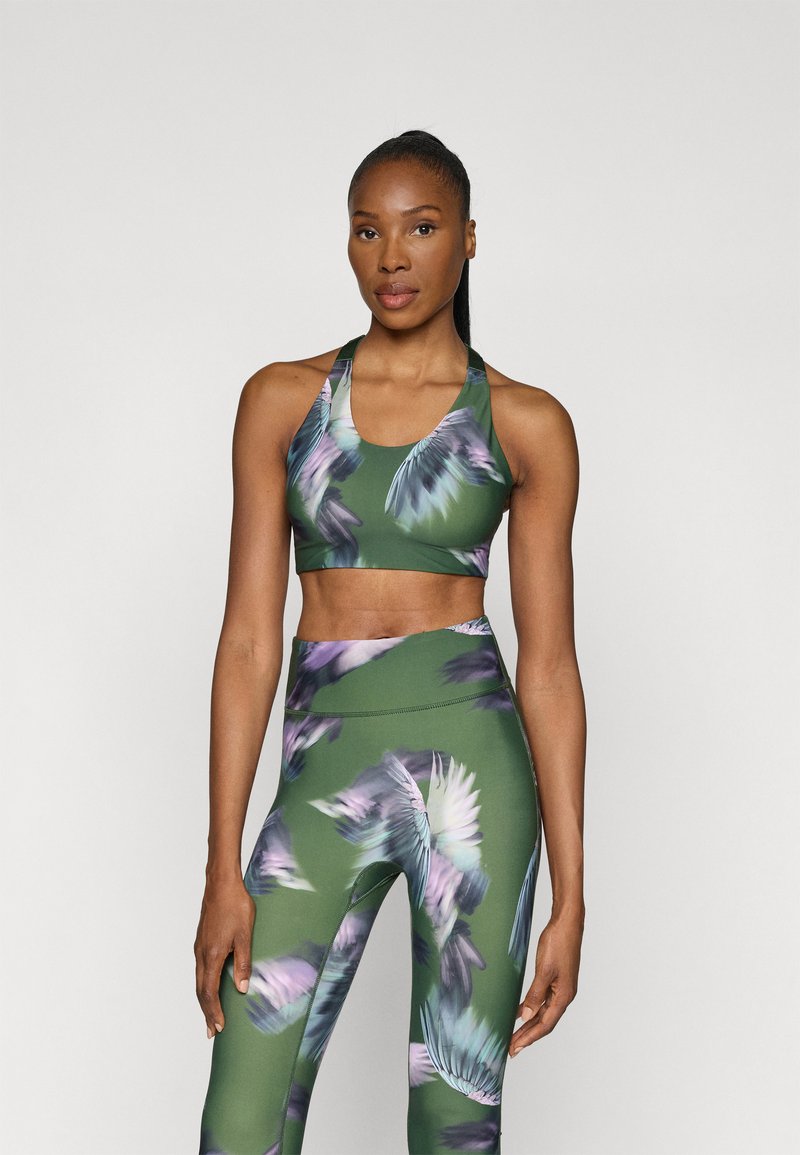 Súprava športovej podprsenky a legín v zelenej farbe s kvetinovým vzorom. Má priliehavý strih, mäkkú látku a strih s priehľadnými ramienkami pre pohodlie a flexibilitu.