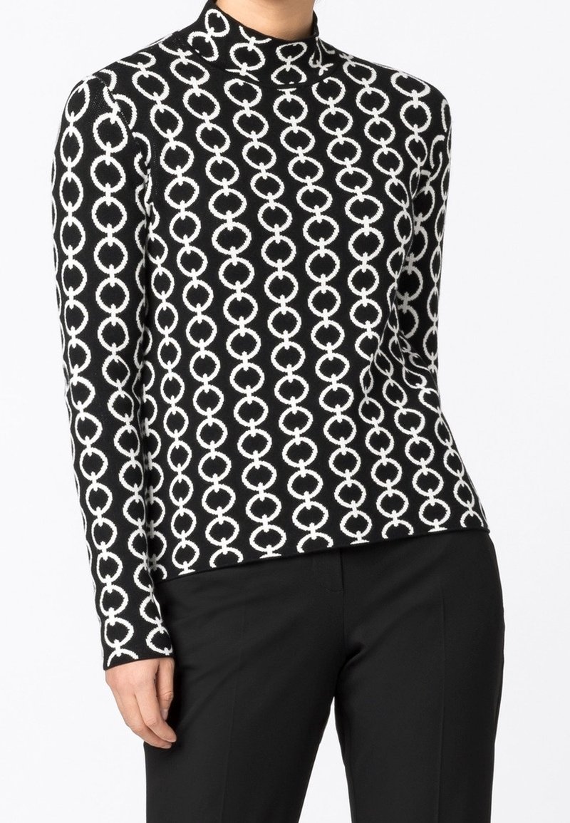 Maglia a maniche lunghe con collo alto, caratterizzata da un motivo circolare in bianco e nero su un tessuto a maglia. Il design è aderente e elegante.