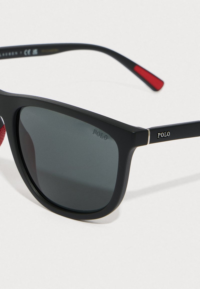 Black, matte-finish sunglasses with dark lenses. Features silver accents, "POLO" branding on the temples, and red detail on the temple tips.