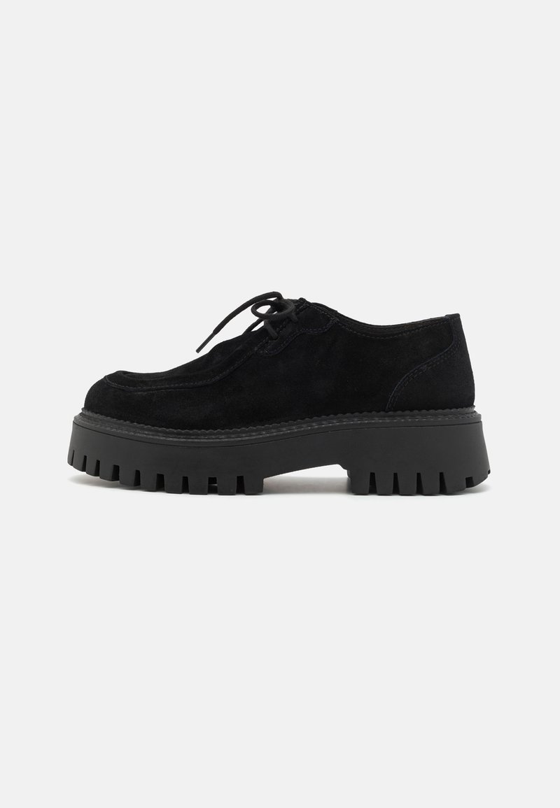 Chaussure en daim noire à lacets avec semelle crantée épaisse et petit talon, montrée de profil sur fond uni.