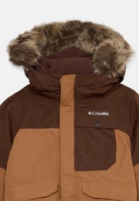 Brown hooded jacket with a fur-lined hood, featuring a zippered front, chest pocket, and large front pockets. The material has a smooth texture.
