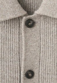 Jasnoszary sweter rozpinany z dzianiny, ozdobiony teksturowanym wzorem prążkowanym, posiadający rozłożysty kołnierz oraz ciemne guziki z przodu.