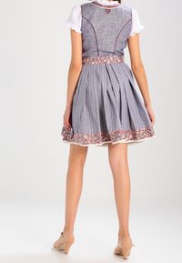 Robe dirndl à motifs bleus avec un corsage ajusté, une jupe plissée, une bordure florale et un détail de jupon en dentelle à l'ourlet.