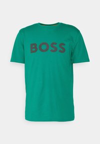 Grøn kortærmet t-shirt lavet af bomuld med rund hals, der har et stort sort "BOSS" logo trykt på forsiden.