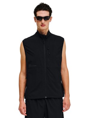 Mann trägt schwarze ärmellose Zip-up-Weste und schwarze Sonnenbrille, steht vor weißem Hintergrund.