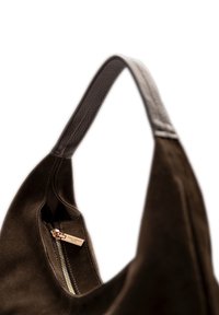 Donkerbruine suède handtas met een gladlederen schouderriem en een ritsluiting met een gouden trekker. Minimalistisch ontwerp met een zachte textuur.