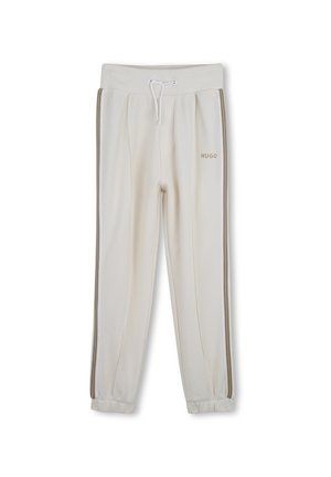 Pantalones jogger color crema con cintura con cordón, franjas laterales y logo "HUGO" en el muslo izquierdo, mostrados sobre un fondo blanco.