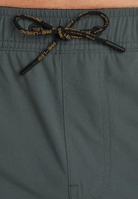 Pantaloni da bagno grigi con cintura elastica, caratterizzati da un laccetto nero con branding giallo e un tessuto liscio e leggero.
