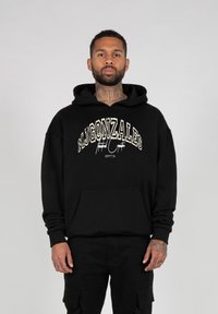 Sort hoodie lavet af blødt stof, med en frontlomme og hvid broderet "MJGONZALES" tekst på tværs af brystet. Standard fit.