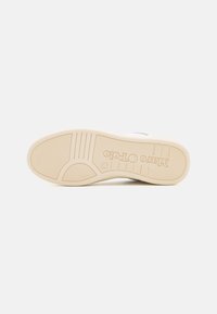 Podeszwa beżowego sneakersa z teksturą gripów i wytłoczonym logo "Marc O'Polo", rozmiar 37 oznaczony w okolicy łuku.