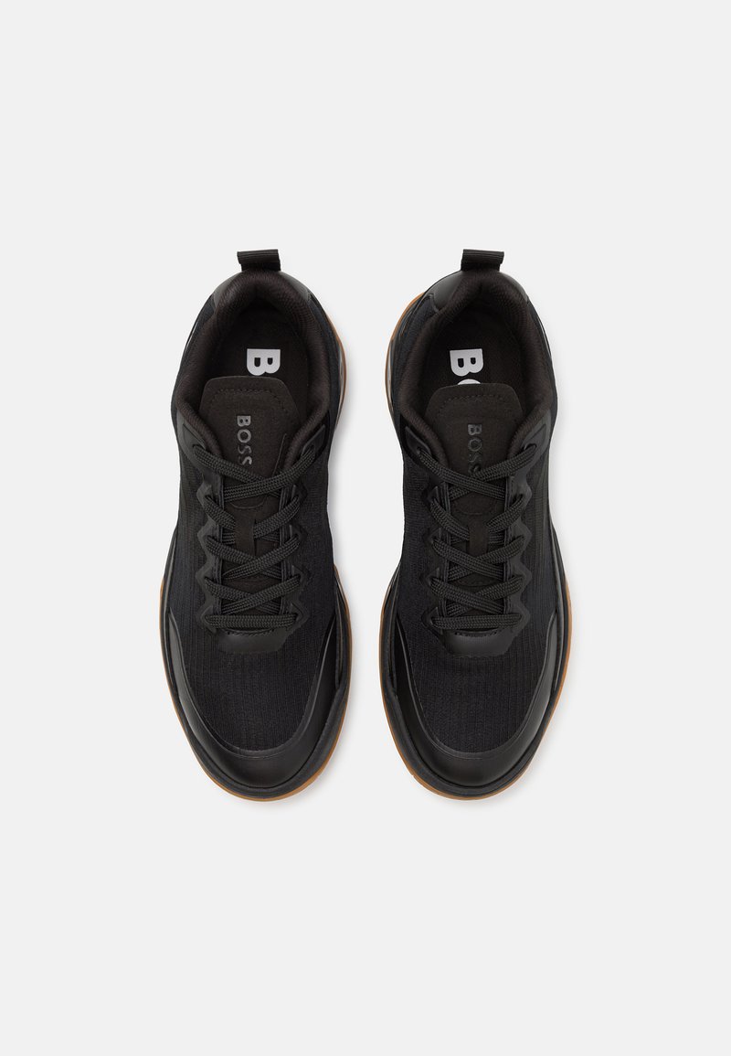 Zwarte sportschoenen met een gestructureerd mesh bovenwerk, ronde neus en rubberen zool. Voorzien van veters en trekbandjes voor gemakkelijk aan- en uittrekken.