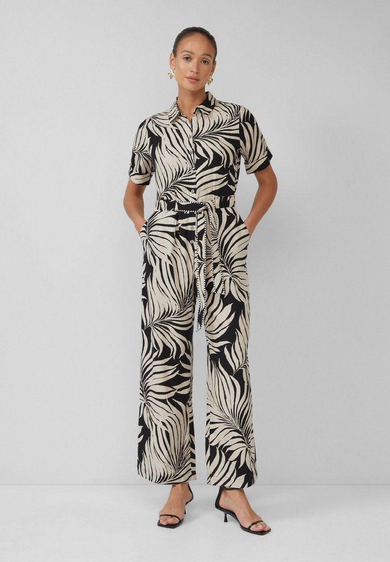 Zwart en beige jumpsuit met een bladerenpatroon, korte mouwen, een knoopsluiting aan de voorkant en een cinched riem in de taille. Ontwerp met wijde benen.