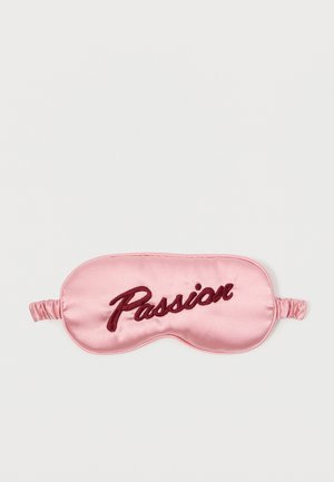 Máscara de sono em cetim rosa com "Paixão" bordado em vermelho escuro, apresentando um formato contornado e uma faixa elástica para um ajuste seguro.