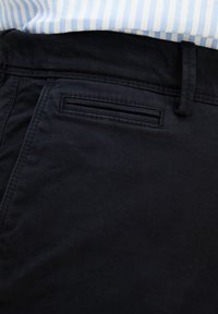 Pantaloni blu navy con una texture liscia e una leggera lucentezza. Presentano un design classico delle tasche e passanti per cintura per una maggiore funzionalità.