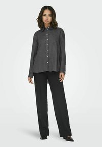 Dark gray button-up shirt with a collar and pocket, paired with black wide-leg pants. Smooth texture, relaxed fit, and full-length sleeves.