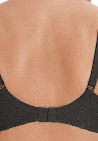 Sort bh med et struktureret design, justerbare stropper og lukning med hægte og øje bagpå. Glat tekstur af stoffet synlig.