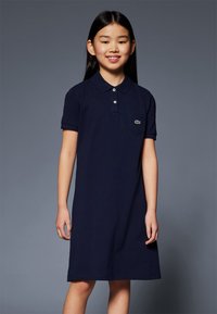 Navyblauw polojurkje van katoen met korte mouwen, een puntige kraag en een klein groen logo op de borstzak.