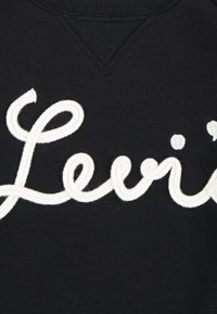 Felpa nera caratterizzata da un logo ricamato in bianco molto visibile. Tessuto liscio con collo a girocollo ribattuto e leggero dettaglio a forma di V.