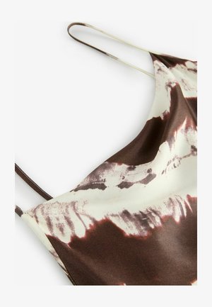 Barna és krém színű mintás spagettipántos top. Puha, sima anyag, amelyen batikolt mintázat található sötétbarna kiemelésekkel.