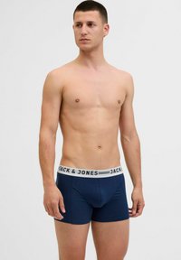 Samarinā zila bokseršortus, kas izgatavoti no mīksta auduma ar baltu elastīgu jostasvietu, uz kuras ir melnā burtu lielumā rakstīts zīmola nosaukums "JACK & JONES".