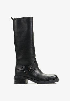 Czarny skórzany kozaki do połowy łydki z niskim, nałożonym obcasem oraz ozdobnym paskiem z metalowym kółkiem i ćwiekami wokół kostki.