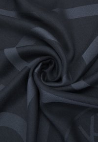 Tessuto nero con una texture e un sottile motivo geometrico, caratterizzato da pieghe morbide e lisce che indicano un materiale leggero e traspirante.