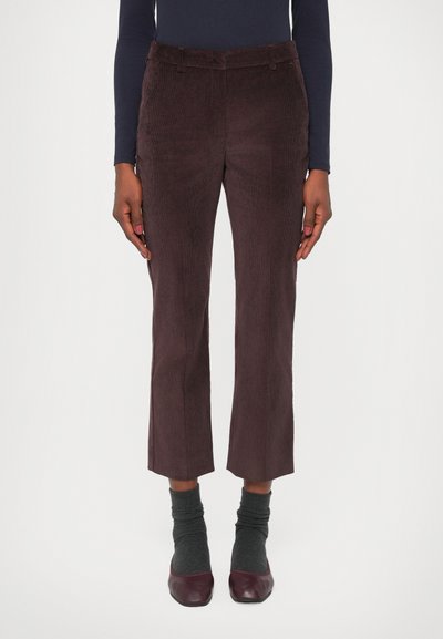 Brown corduroy cropped trousers with a straight leg cut, featuring a smooth texture and belt loops. Worn with grey socks and burgundy flats.