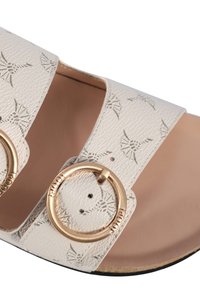 Bílé kožené sandály s texturovaným povrchem a vzorem listů, dvě široké pásky a kroužkové spony ve zlatém odstínu. Součástí je plochá podrážka.