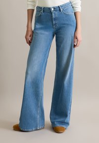 Helleblaue weit geschnittene Jeans aus Denim. Mit fünf Taschen, Gürtelschlaufen und einem Reißverschluss mit Knopfverschluss.
