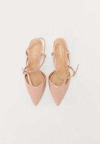 Rosa patent lær slingback hæle med spidse tæer, ankelremme og detaljer i guldfarvet hardware. Glat tekstur, minimalistisk design.