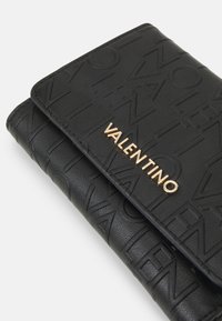 Černá kožená peněženka s embosovaným vzorem a zlatým logem "VALENTINO". Design zahrnuje texturovaný povrch a kompaktní tvar.
