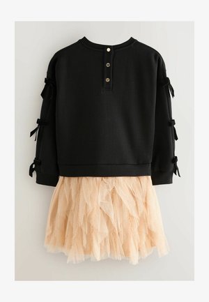 Melnas sporta krekls ar pogu detaļām un sānu lentēm, apvienots ar persiku krāsas, viļņotu tilla svārku, kurā ir smalks mirdzums.