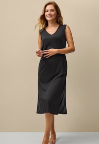 Mouwloze zwarte jurk met een V-hals, knielange snit en zijslits, gemaakt van licht, zacht materiaal met een gladde textuur.