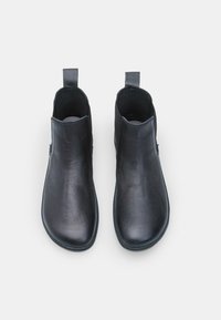 Černé kožené kotníkové boty s hladkou texturou, zaoblenou špičkou a poutky na patě. Mají minimalistický design bez viditelného kování.