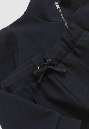 Czarna bluza z kapturem na zamek błyskawiczny, wykonana z materiału przypominającego sweatshirt, z przednią kieszenią z sznurkiem i metalowymi oczkami, o gładkiej teksturze.