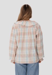 Camisa de cuadros multicolores en tejido ligero con un cuello con volantes y mangas largas. La vista trasera muestra pliegues y suaves tonos pastel.