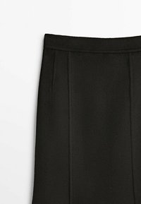 Jupe noire taille haute à coupe droite, avec des détails de coutures verticales et une large ceinture sur fond blanc uni.