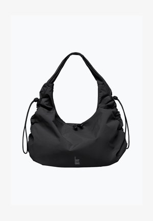 Black bag made of textured fabric, featuring a slouchy design, wide shoulder strap, and drawstring closure for adjustable shape.