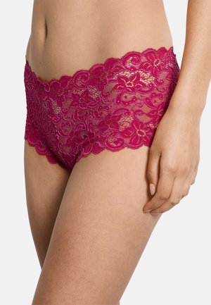 Torso femenino con ropa interior tipo hipster de encaje floral color burdeos, mano derecha apoyada en el muslo sobre fondo blanco.