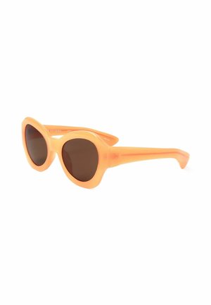 Occhiali da sole rotondi stile cat-eye con montatura spessa color pesca e lenti scure, mostrati leggermente inclinati su sfondo bianco.