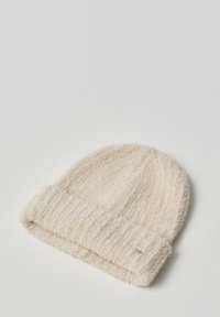 Cream-colored knitted beanie hat with a ribbed cuff, made of soft, fuzzy yarn with subtle shimmering accents. Round shape, warm texture.